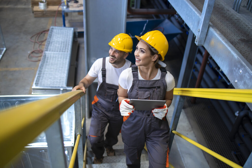 Industrial workers engineers walking in factory and climbing metal stairs.